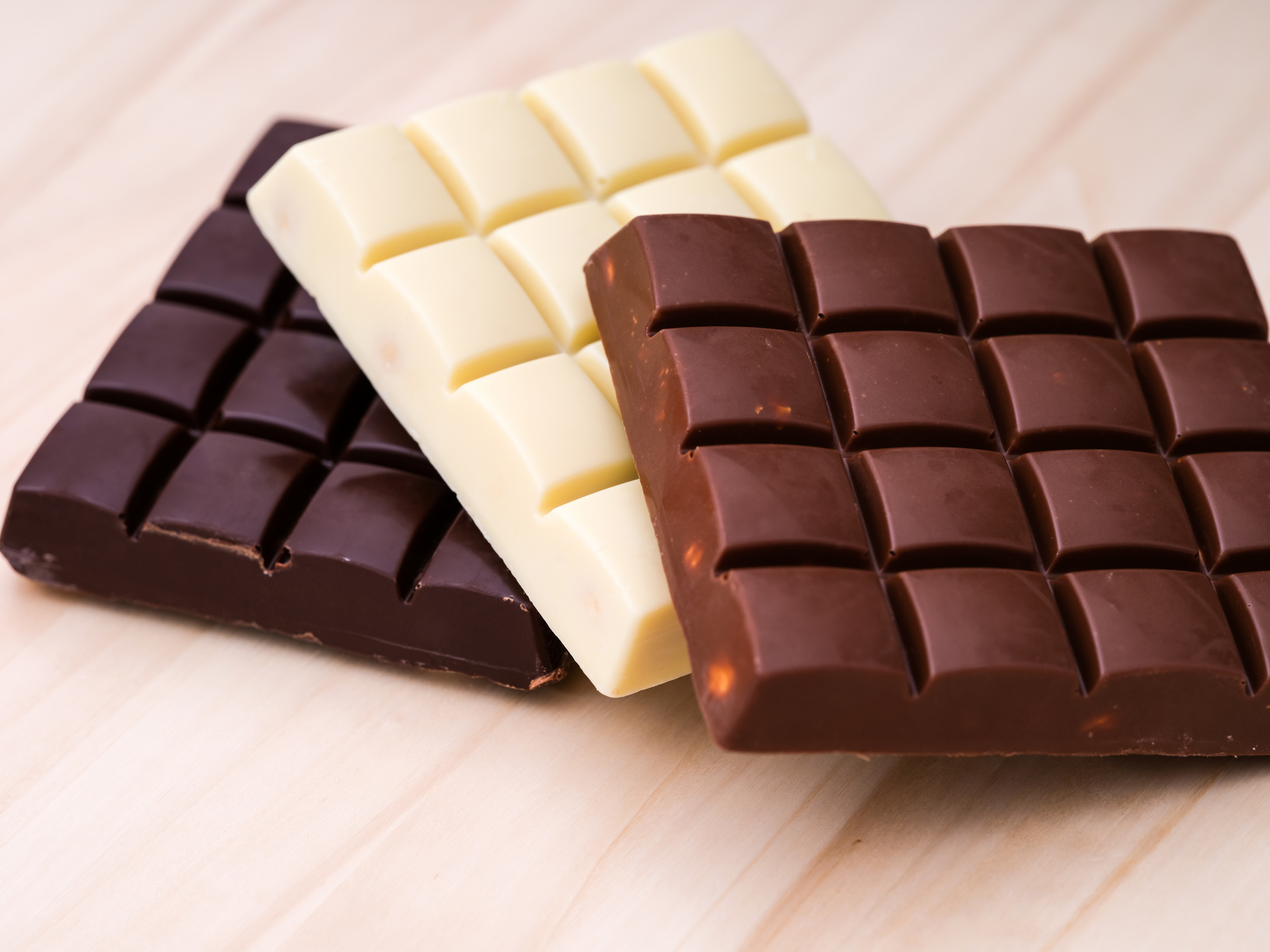 Chocolate bars - milk chocolate, dark chocolate and white chocolate on wooden background.